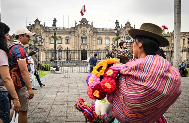 Pedestrians walk through Lima's Plaza de Armas in front of the Government Palace, in the historic center of the Peruvian capital. on June 6, 2026 ahead of the presidential runoff. Right-wing candidate Keiko Fujimori and leftist Roberto Sanchez will face off in Peru's presidential runoff on June 7, 2026. (Photo by MARTIN BERNETTI / AFP)