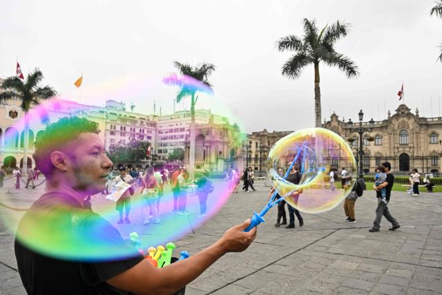 A street vendor blows soap bubbles at Lima's Plaza de Armas in front of the Government Palace, in the historic center of the Peruvian capital. on June 6, 2026 ahead of the presidential runoff. Right-wing candidate Keiko Fujimori and leftist Roberto Sanchez will face off in Peru's presidential runoff on June 7, 2026. (Photo by MARTIN BERNETTI / AFP)