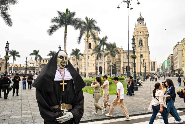 A man disguised as The Nun movie character stands at Lima's Plaza de Armas in front of the Government Palace, in the historic center of the Peruvian capital. on June 6, 2026 ahead of the presidential runoff. Right-wing candidate Keiko Fujimori and leftist Roberto Sanchez will face off in Peru's presidential runoff on June 7, 2026. (Photo by MARTIN BERNETTI / AFP)