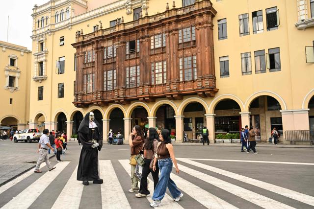 Pedestrians walk through Lima's Plaza de Armas in front of the Government Palace, in the historic center of the Peruvian capital. on June 6, 2026 ahead of the presidential runoff. Right-wing candidate Keiko Fujimori and leftist Roberto Sanchez will face off in Peru's presidential runoff on June 7, 2026. (Photo by MARTIN BERNETTI / AFP)