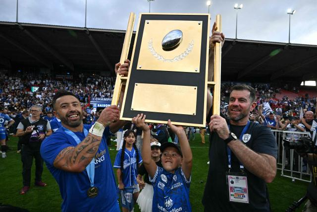 Vannes' New Zealand scrum-half Michael Ruru and a Vannes' co-coach Goulven Le Garrec hold the shield at the end of the French Pro D2 rugby union final match between RC Vannes and Provence Rugby at the Ernest Wallon Stadium in Toulouse, southwestern France, on June 6, 2026. (Photo by Lionel BONAVENTURE / AFP)