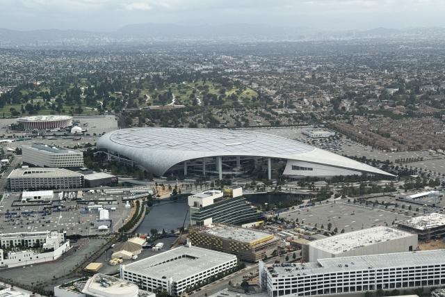 (FILES) An aerial image shows Los Angeles Stadium, temporarily renamed from SoFi Stadium, and the KIA Forum (Rear) ahead of the FIFA World Cup 2026 in Inglewood, California, on May 27, 2026. Workers at SoFi Stadium in Los Angeles have overwhelmingly voted to authorize a potential strike on June 6, 2026 during the World Cup, just days before football's global showpiece begins. The Unite Here Local 11 union, which represents about 2,000 stadium food and beverage workers, is demanding better pay along with assurances that federal immigration agents will not be allowed to enter the venue. (Photo by Patrick T. Fallon / AFP)