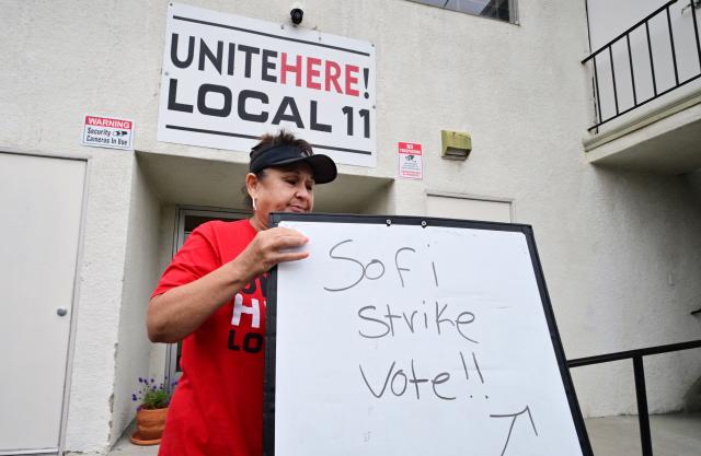 (FILES) Yolanda Fierro, a suites runner at SoFi Stadium, moves a sign into position at union headquarters where stadium workers will vote on whether to authorize a strike amid a contract dispute, days before the 2026 FIFA World Cup begins in Inglewood, California, on June 4, 2026. Workers at SoFi Stadium in Los Angeles have overwhelmingly voted to authorize a potential strike on June 6, 2026 during the World Cup, just days before football's global showpiece begins. The Unite Here Local 11 union, which represents about 2,000 stadium food and beverage workers, is demanding better pay along with assurances that federal immigration agents will not be allowed to enter the venue. (Photo by Frederic J. BROWN / AFP)