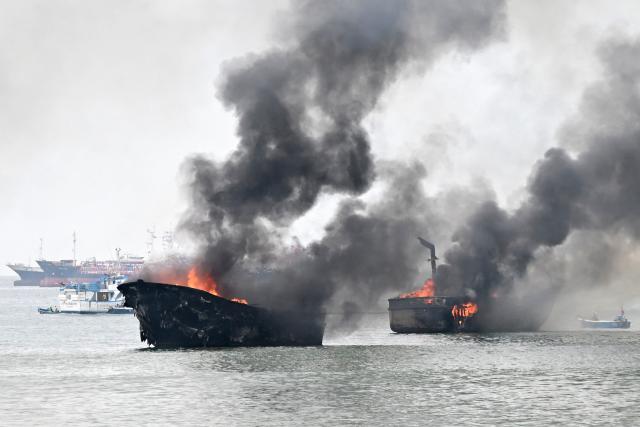 Fishing boats burn near the port of Manta, Ecuador on June 6, 2026. At least 35 fishing boats were destroyed and two people were injured in a major fire that broke out at a crowded dock in western Ecuador on June 6, 2026, according to the Risk Management Secretariat. The Ecuadorian Police stated in a press release that "the incident appears to have occurred while welding work was being carried out on a boat" and ruled out the possibility that it was an attack by criminal groups. (Photo by Ariel OCHOA / AFP)