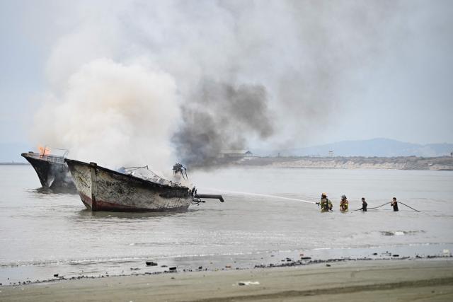 Ecuadorian firefighters extinguish a fire on a fishing boat near the port of Manta, Ecuador on June 6, 2026. At least 35 fishing boats were destroyed and two people were injured in a major fire that broke out at a crowded dock in western Ecuador on June 6, 2026, according to the Risk Management Secretariat. The Ecuadorian Police stated in a press release that "the incident appears to have occurred while welding work was being carried out on a boat" and ruled out the possibility that it was an attack by criminal groups. (Photo by Ariel OCHOA / AFP)
