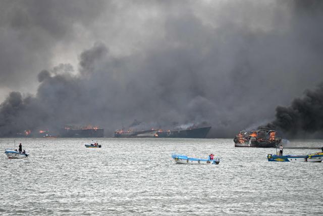 Fishing boats burn near the port of Manta, Ecuador on June 6, 2026. At least 35 fishing boats were destroyed and two people were injured in a major fire that broke out at a crowded dock in western Ecuador on June 6, 2026, according to the Risk Management Secretariat. The Ecuadorian Police stated in a press release that "the incident appears to have occurred while welding work was being carried out on a boat" and ruled out the possibility that it was an attack by criminal groups. (Photo by Ariel OCHOA / AFP)