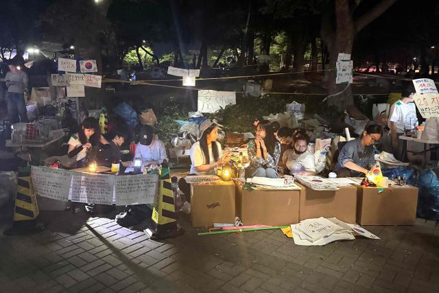 South Korean protesters demanding a rerun of the local elections due to a shortage of ballot papers stage a sit-in protest outside a ballot counting station in Seoul on June 7, 2026. Thousands of South Koreans were demanding a rerun of local elections as they protested into the wee hours of June 7, over ballot paper shortages that disrupted this week's vote. (Photo by Claire LEE / AFP)