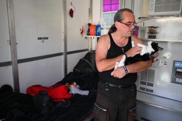 Michael Gilpin holds their cat where they live inside a Tiny Home Village of Pallet Shelters managed by Hope The Mission for homeless interim housing in the Eagle Rock neighborhood of Los Angeles, California on June 1, 2026. Los Angeles, the second-largest US city prepares to host eight World Cup soccer matches this summer, followed by the 2028 Olympics. Infamous for its squalid encampments—located right on the sidewalks or beneath massive highway overpasses—the "City of Angels" has been pulling out all the stops over the past three years to house its homeless population. Democratic Mayor Karen Bass has made this a top priority, ramping up initiatives to fund thousands of housing spots, whether in hotels or in "tiny homes" (Photo by Patrick T. Fallon / AFP)