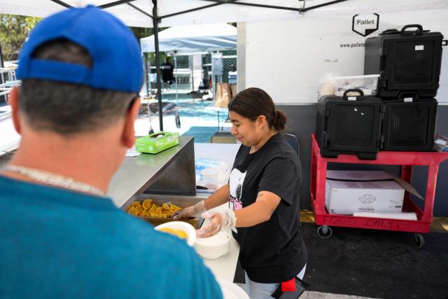 Staff serve fresh fruit and food to a resident in a Tiny Home Village managed by Hope The Mission for interim homeless housing in the Eagle Rock neighborhood of Los Angeles, California on June 1, 2026. Los Angeles, the second-largest US city prepares to host eight World Cup soccer matches this summer, followed by the 2028 Olympics. Infamous for its squalid encampments—located right on the sidewalks or beneath massive highway overpasses—the "City of Angels" has been pulling out all the stops over the past three years to house its homeless population. Democratic Mayor Karen Bass has made this a top priority, ramping up initiatives to fund thousands of housing spots, whether in hotels or in "tiny homes" (Photo by Patrick T. Fallon / AFP)