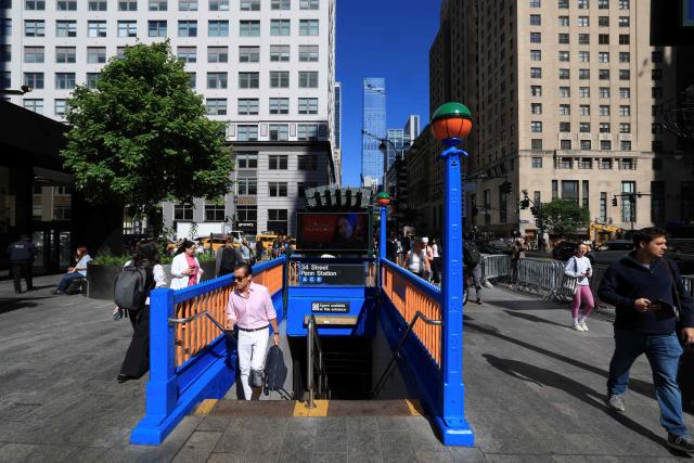 (FILES) People walk past a blue and orange subway entrance honoring the New York Knicks near Madison Square Garden in New York City on June 2, 2026, after the team advanced to the NBA Finals, where it will face the San Antonio Spurs. As New York prepares to host the World Cup, the city is instead awash in Knicks blue and orange, reflecting a deep love for the gritty, unifying team chasing a historic NBA Finals victory. The Knicks took a commanding 2-0 lead on June 5 in the best of seven series against the San Antonio Spurs, and now the action shifts to the Big Apple for games three and four. (Photo by Timothy A. CLARY / AFP)