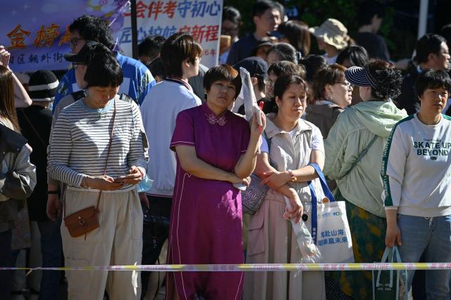 Parents (Back) wait outside a shcool as students line up to enter a school on the first day of China's National College Entrance Examination (NCEE) known as "gaokao", in Beijing on June 7, 2026. (Photo by WANG Zhao / AFP)