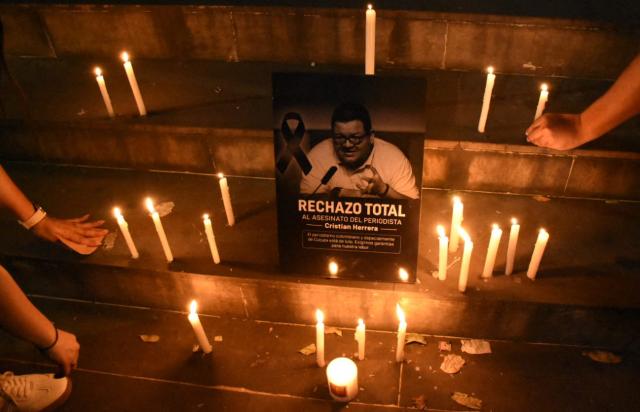 People light candles around a a sign in tribute to Colombian journalist Cristian Herrera during a vigil held following his murder in Cucuta, Colombia on June 6, 2026. Herrera was killed on June 6, 2026, on the Colombia-Venezuela border, following the death of another journalist attacked by guerrillas nearly a month ago according to the Ombudsman's Office. (Photo by Mauricio Saenz / AFP)