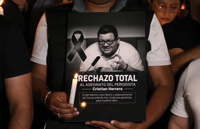 A man shows a sign in tribute to Colombian journalist Cristian Herrera during a vigil held following his murder in Cucuta, Colombia on June 6, 2026. Herrera was killed on June 6, 2026, on the Colombia-Venezuela border, following the death of another journalist attacked by guerrillas nearly a month ago according to the Ombudsman's Office. (Photo by Mauricio Saenz / AFP)