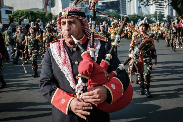 A member of the Royal Jordanian Army band plays the bagpipes alongside members of the marching band of the Indonesian Defence University during a street parade celebrating Jordan's Independence Day, which is celebrated annually on May 25, in Jakarta on June 7, 2026. (Photo by Yasuyoshi Chiba / AFP)