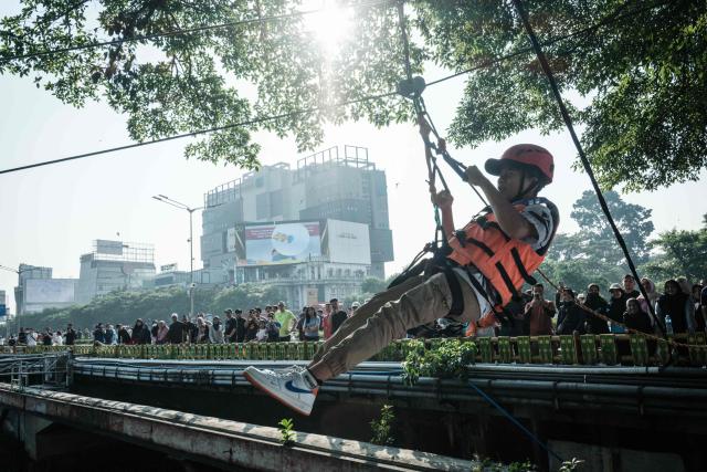 A man glides across the Ciliwung River on a zip line in Jakarta on June 7, 2026. (Photo by Yasuyoshi Chiba / AFP)