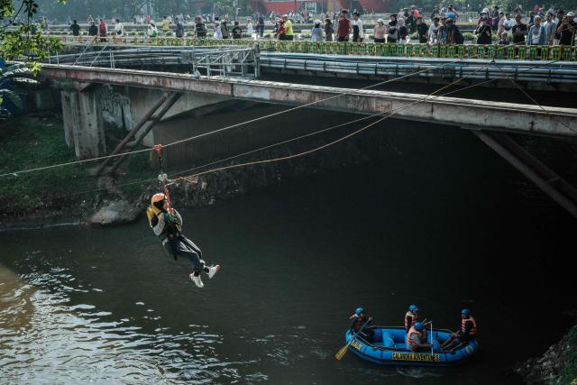 A woman glides across the Ciliwung River on a zip line in Jakarta on June 7, 2026. (Photo by Yasuyoshi Chiba / AFP)