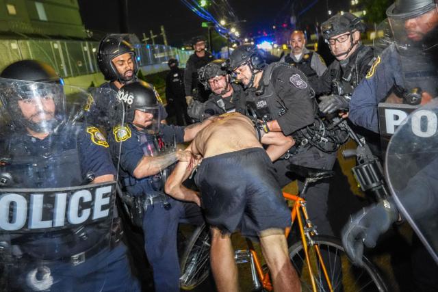 Newark police officers detain a protester outside Delaney Hall, which is being used as an Immigration and Customs Enforcement (ICE) detention center, in Newark, New Jersey on June 6, 2026. The US state of New Jersey on June 2, 2026, sued the private prison company that runs the migrant detention center where protesters have rallied for several days over allegedly poor conditions at the jail. The lawsuit against GEO Group demands that local health authorities be allowed full access to Delaney Hall, one of many facilities holding people rounded up in US President Donald Trump's mass deportation sweep. (Photo by Ryan MURPHY / AFP)