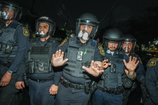 Newark police officers gesture as they push protesters back outside Delaney Hall, which is being used as an Immigration and Customs Enforcement (ICE) detention center, in Newark, New Jersey on June 6, 2026. The US state of New Jersey on June 2, 2026, sued the private prison company that runs the migrant detention center where protesters have rallied for several days over allegedly poor conditions at the jail. The lawsuit against GEO Group demands that local health authorities be allowed full access to Delaney Hall, one of many facilities holding people rounded up in US President Donald Trump's mass deportation sweep. (Photo by Ryan MURPHY / AFP)