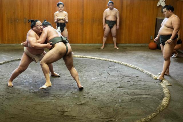 Sumo wrestler Dewanoryu (L) trains in the dohyo, a wrestling ring, as other wrestlers look on at the Dewanoumi sumo stable in Tokyo on June 4, 2026. The stable, founded in 1862 and one of the sport's oldest, has become a major lineage in modern sumo, producing many top-division wrestlers. (Photo by Andrew CABALLERO-REYNOLDS / AFP)