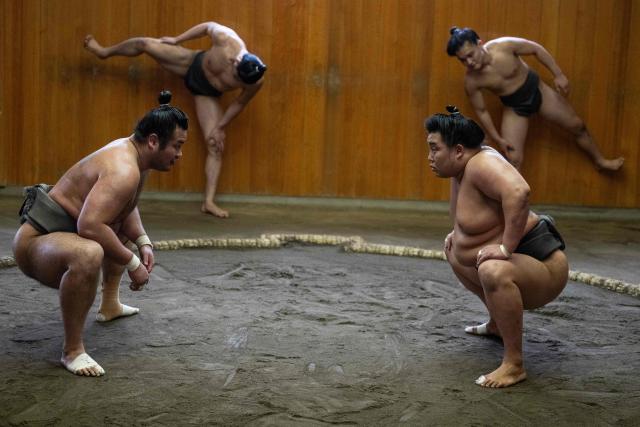 Sumo wrestler Dewanoryu (R) trains as others stretch in the dohyo, a wrestling ring, at the Dewanoumi sumo stable in Tokyo on June 4, 2026. The stable, founded in 1862 and one of the sport's oldest, has become a major lineage in modern sumo, producing many top-division wrestlers. (Photo by Andrew CABALLERO-REYNOLDS / AFP)