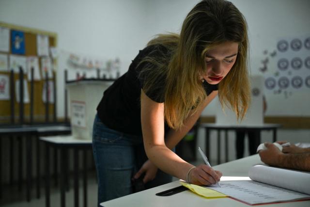 A woman writes on an official voter register before casting her ballot at a polling station for general elections in Pristina on June 7, 2026. Polls opened on June 7, 2026 for another snap election in Kosovo, its third in just over a year, as voter frustration mounts at a grinding political gridlock in Europe's youngest country, as the ballot comes after a polarised parliament failed to elect a president in April, deepening a political crisis that has gripped the country since inconclusive parliamentary elections in February 2025. (Photo by Armend NIMANI / AFP)