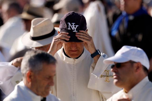 A priest adjusts his cap before the Holy Mass to be led by Pope Leo XIV in the Plaza de Cibeles in Madrid on June 7, 2026. Pope Leo XIV is visiting Spain June 6-12 with stops in Madrid, Barcelona, and the Canary Islands, where he will meet with migrants and organisations dedicated to helping them. (Photo by Oscar DEL POZO / AFP)