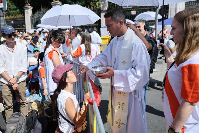 A priest gives Communion to a believer during the Holy Mass led by Pope Leo XIV in the Plaza de Cibeles in Madrid on June 7, 2026. Pope Leo XIV is visiting Spain June 6-12 with stops in Madrid, Barcelona, and the Canary Islands, where he will meet with migrants and organisations dedicated to helping them. (Photo by Thomas COEX / AFP)