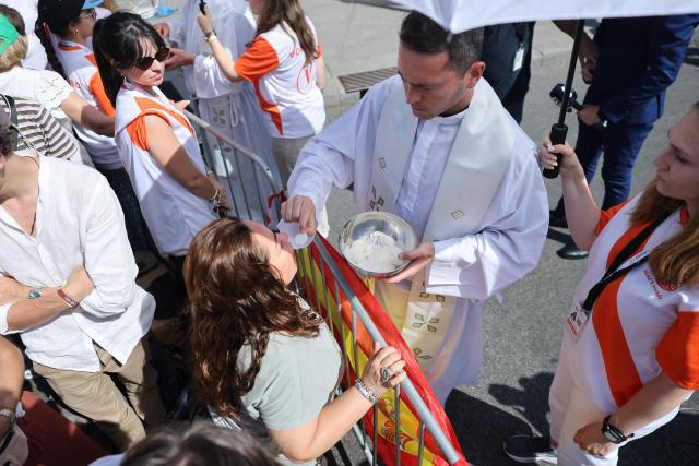 A priest gives Communion to a believer during the Holy Mass led by Pope Leo XIV in the Plaza de Cibeles in Madrid on June 7, 2026. Pope Leo XIV is visiting Spain June 6-12 with stops in Madrid, Barcelona, and the Canary Islands, where he will meet with migrants and organisations dedicated to helping them. (Photo by Thomas COEX / AFP)