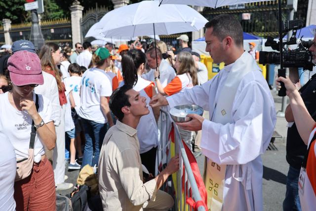 A priest gives Communion to a believer during the Holy Mass led by Pope Leo XIV in the Plaza de Cibeles in Madrid on June 7, 2026. Pope Leo XIV is visiting Spain June 6-12 with stops in Madrid, Barcelona, and the Canary Islands, where he will meet with migrants and organisations dedicated to helping them. (Photo by Thomas COEX / AFP)
