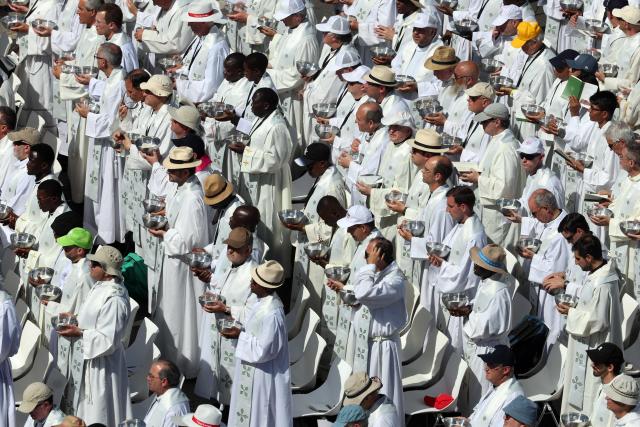 Priests hold ciboria containing the sacred hosts before administering Communion to the faithful in the streets adjacent to Cibeles Square, during the Holy Mass led by Pope Leo XIV in Madrid on June 7, 2026. Pope Leo XIV is visiting Spain June 6-12 with stops in Madrid, Barcelona, and the Canary Islands, where he will meet with migrants and organisations dedicated to helping them. (Photo by Pierre-Philippe MARCOU / AFP)
