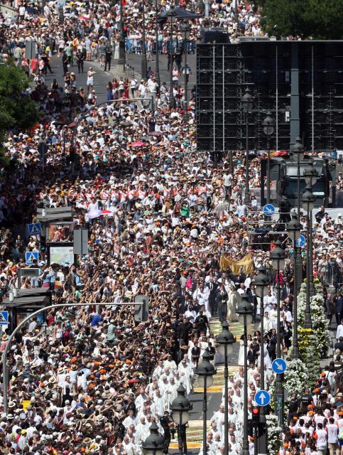 The crowd packs Alcala street as Pope Leo XIV walks under a processional canopy holding the monstrance containing the sacred host during the Corpus Christi procession following the Holy Mass held in the Plaza de Cibeles in Madrid on June 7, 2026. Pope Leo XIV is visiting Spain June 6-12 with stops in Madrid, Barcelona, and the Canary Islands, where he will meet with migrants and organisations dedicated to helping them. (Photo by Pierre-Philippe MARCOU / AFP)