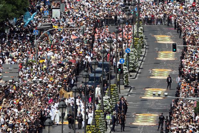 The crowd packs Alcala street as Pope Leo XIV walks under a processional canopy holding the monstrance containing the sacred host during the Corpus Christi procession following the Holy Mass held in the Plaza de Cibeles in Madrid on June 7, 2026. Pope Leo XIV is visiting Spain June 6-12 with stops in Madrid, Barcelona, and the Canary Islands, where he will meet with migrants and organisations dedicated to helping them. (Photo by Pierre-Philippe MARCOU / AFP)