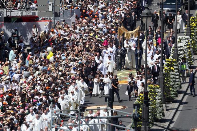 The crowd packs Alcala street as Pope Leo XIV walks under a processional canopy holding the monstrance containing the sacred host during the Corpus Christi procession following the Holy Mass held in the Plaza de Cibeles in Madrid on June 7, 2026. Pope Leo XIV is visiting Spain June 6-12 with stops in Madrid, Barcelona, and the Canary Islands, where he will meet with migrants and organisations dedicated to helping them. (Photo by Pierre-Philippe MARCOU / AFP)