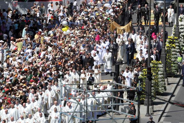 The crowd packs Alcala street as Pope Leo XIV walks under a processional canopy holding the monstrance containing the sacred host during the Corpus Christi procession following the Holy Mass held in the Plaza de Cibeles in Madrid on June 7, 2026. Pope Leo XIV is visiting Spain June 6-12 with stops in Madrid, Barcelona, and the Canary Islands, where he will meet with migrants and organisations dedicated to helping them. (Photo by Pierre-Philippe MARCOU / AFP)