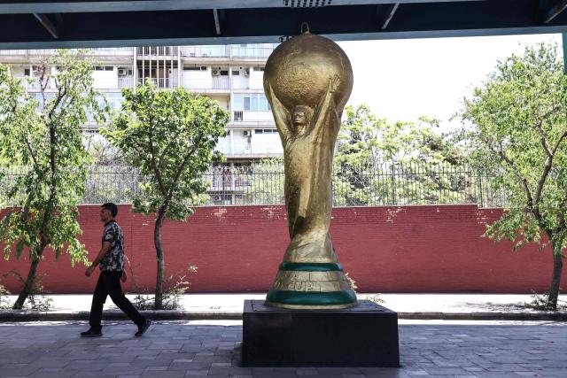 An Iranian man walks past a World Cup trophy displayed under a bridge in Tehran on June 7, 2026. Iran's national team, also known as Team Melli, open their 2026 World Cup campaign, co-hosted by the United States, Mexico and Canada, against New Zealand in Los Angeles on June 15 before lining up against Belgium and Egypt in Group G. Iran has been at war with the United States and Israel since February 28, though a fragile ceasefire has been in place since April 8. Tehran and Washington have had no diplomatic relations since 1980 following the hostage crisis at the US embassy, which came after the Islamic revolution that toppled the US-backed shah. (Photo by ATTA KENARE / AFP)