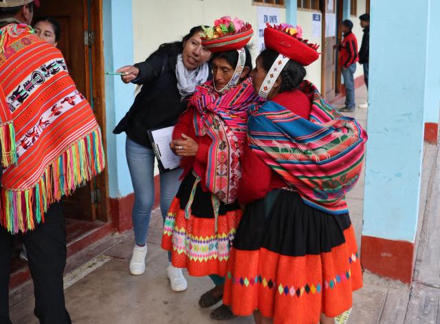 An election staffer gives information to local residents during the presidential election runoff at a polling station in Ollantaytambo, department of Cusco, Peru, on June 7, 2026. Peruvians will choose their ninth president in 10 years in a tight runoff election between conservative Keiko Fujimori and leftist Roberto Sanchez, who are trying to woo voters fed up with political chaos and rising crime. (Photo by Jose Angulo / AFP)
