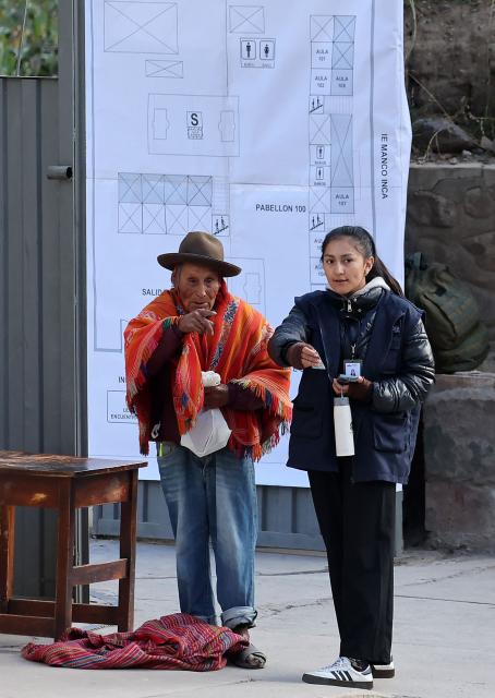 An election staffer gives information to a local resident during the presidential election runoff at a polling station in Ollantaytambo, department of Cusco, Peru, on June 7, 2026. Peruvians will choose their ninth president in 10 years in a tight runoff election between conservative Keiko Fujimori and leftist Roberto Sanchez, who are trying to woo voters fed up with political chaos and rising crime. (Photo by Jose Angulo / AFP)