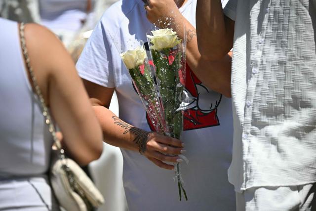 An attendee holds roses as relatives and people prepare to take part in a silent march in tribute to Lyhanna, an 11-year-old girl found dead on June 4 after having been reported missing since May 29, 2026, in Fleurance, southwestern France, on June 7, 2026. Outrage has erupted in France after it emerged the main suspect Jerome.B, a 41-year-old father of two, had been repeatedly accused of sexually abusing children but no action was taken to protect others. (Photo by Lionel BONAVENTURE / AFP)