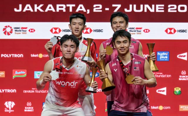 Winners Malaysia's Goh Sze Fei and Nur Izzuddin pose with runners-up Indonesia's Raymond Indra and Nikolaus Joaquin during the medal ceremony after their men's doubles final match at the Indonesia Open badminton tournament in Jakarta on June 7, 2026. (Photo by BAY ISMOYO / AFP)