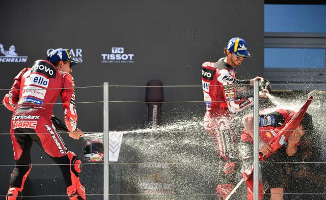 Winner Team Ducati Lenovo Team's Marc Marquez (L) and third placed Team Ducati Lenovo Team's Francesco Bagnaia douse a staff member with champagne as they celebrate on the podium of the Hungarian Motorcycle MotoGP Grand Prix at the Balaton Park circuit in Balatonfokajar, Hungary, on June 7, 2026. (Photo by Ferenc ISZA / AFP)
