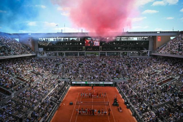 Smoke in the colours of the French flag are seen over Court Philippe-Chatrier during the ceremony ahead of the men's final singles match on day 15 of the French Open tennis tournament at the Roland-Garros Complex in Paris on June 7, 2026. (Photo by JULIEN DE ROSA / AFP)