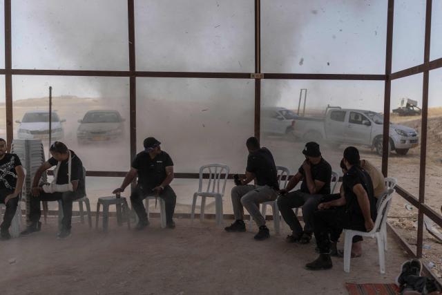 People try to take cover from a sandstorm at the Bedouin community of Tel Arad, that is being self demolished ahead of a date that was given to the residents by Israeli authorities in Negev desert, in southern Israel on June 7, 2026. (Photo by Ilia YEFIMOVICH / AFP)