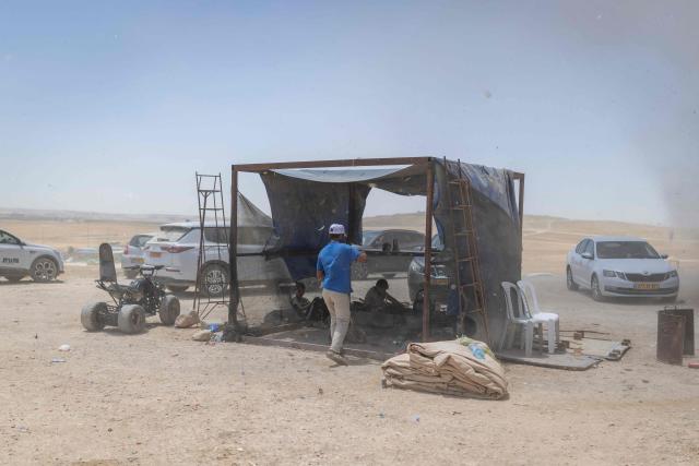 People try to take cover from a sandstorm at the Bedouin community of Tel Arad, that is being self demolished ahead of a date that was given to the residents by Israeli authorities in Negev desert, in southern Israel on June 7, 2026. (Photo by Ilia YEFIMOVICH / AFP)