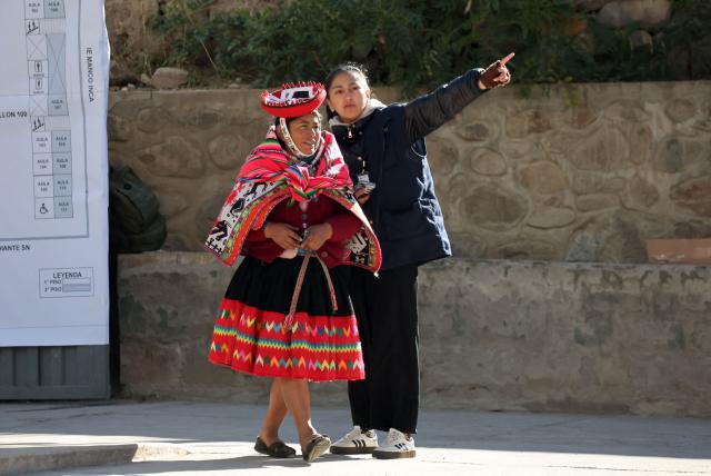 An election staffer helps a voter during the presidential election runoff at a polling station in Ollantaytambo, Cusco department, Peru, on June 7, 2026. Peruvians will choose their ninth president in 10 years in a tight runoff election between conservative Keiko Fujimori and leftist Roberto Sanchez, who are trying to woo voters fed up with political chaos and rising crime. (Photo by Jose Angulo / AFP)