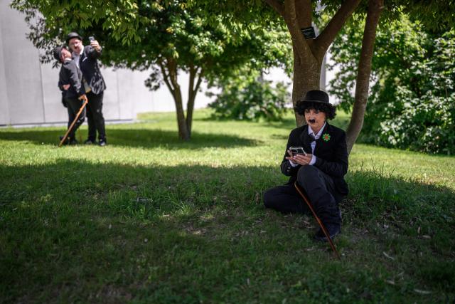 People dressed as "The Tramp" pose for a photograph next to The Manoir de Ban, the final residence of English filmm director and actor Charlie Chaplin, during an event to celebrate the 10th anniversary of the Chaplin's World museum in Corsier-sur-Vevey, western Switzerland, on June 7, 2026. Some 429 people took part in the event. (Photo by Fabrice COFFRINI / AFP)