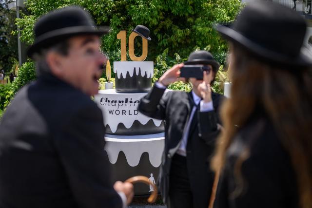 People dressed as "The Tramp" pose for a photograph next to The Manoir de Ban, the final residence of English film director and actor Charlie Chaplin, during an event to celebrate the 10th anniversary of the Chaplin's World museum in Corsier-sur-Vevey, western Switzerland, on June 7, 2026. Some 429 people took part in the event. (Photo by Fabrice COFFRINI / AFP)