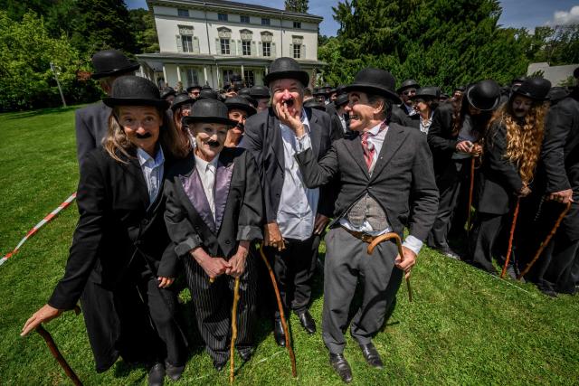 People dressed as "The Tramp" pose for a photograph next to The Manoir de Ban, the final residence of English film director and actor Charlie Chaplin, during an event to celebrate the 10th anniversary of the Chaplin's World museum in Corsier-sur-Vevey, western Switzerland, on June 7, 2026. Some 429 people took part in the event. (Photo by Fabrice COFFRINI / AFP)