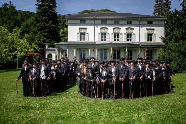 TOPSHOT - People dressed as "The Tramp" pose for a photograph next to The Manoir de Ban, the final residence of English film director and actor Charlie Chaplin, during an event to celebrate the 10th anniversary of the Chaplin's World museum in Corsier-sur-Vevey, western Switzerland, on June 7, 2026. Some 429 people took part in the event. (Photo by Fabrice COFFRINI / AFP)