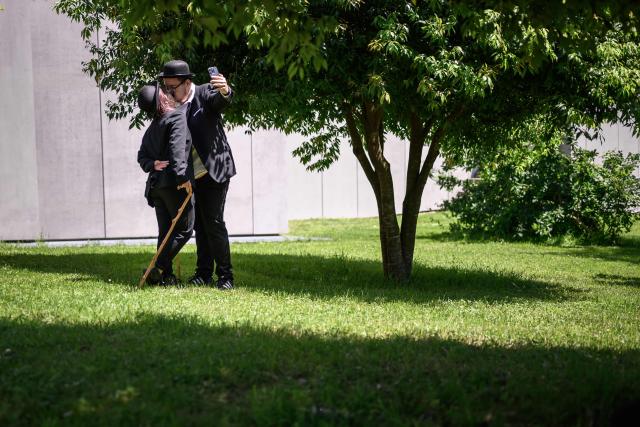 A couple dressed as "The Tramp"  kisses for a selfie next to The Manoir de Ban, the final residence of English film director and actor Charlie Chaplin, during an event to celebrate the 10th anniversary of the Chaplin's World museum in Corsier-sur-Vevey, western Switzerland on June 7, 2026. Some 429 people took part in the event. (Photo by Fabrice COFFRINI / AFP)