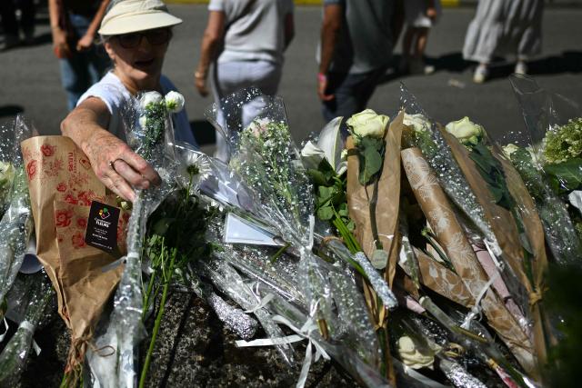 A person lays a flower outside the school at the end of a silent march in tribute to Lyhanna, an 11-year-old girl found dead on June 4 after having been reported missing since May 29, in Fleurance, southwestern France, on June 7, 2026. Outrage has erupted in France after it emerged the main suspect Jerome.B, a 41-year-old father of two, had been repeatedly accused of sexually abusing children but no action was taken to protect others. The inscription on the jerseys reads : "Never again !". (Photo by Lionel BONAVENTURE / AFP)